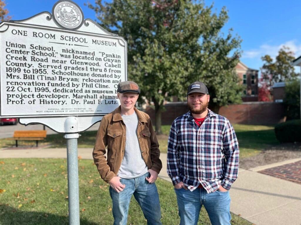 One Room School House Students in front of sign