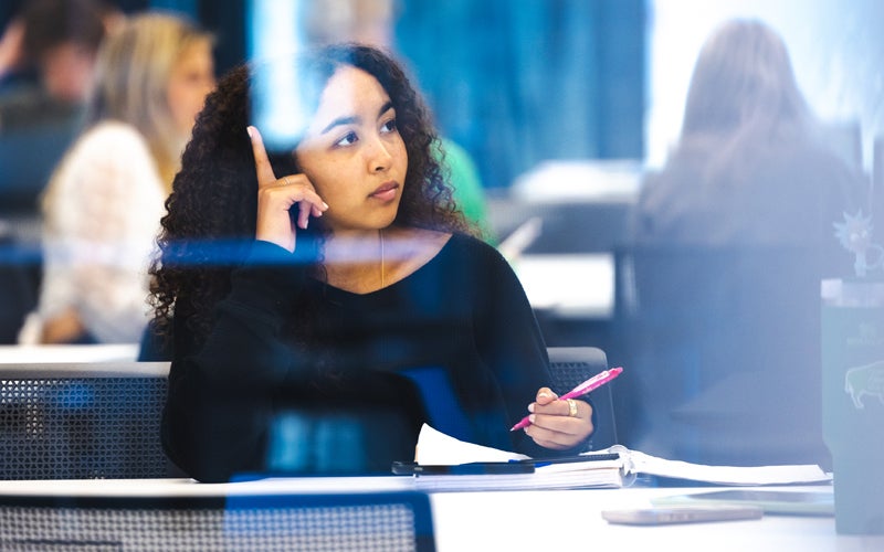 A student listens to a class lecture while taking notes