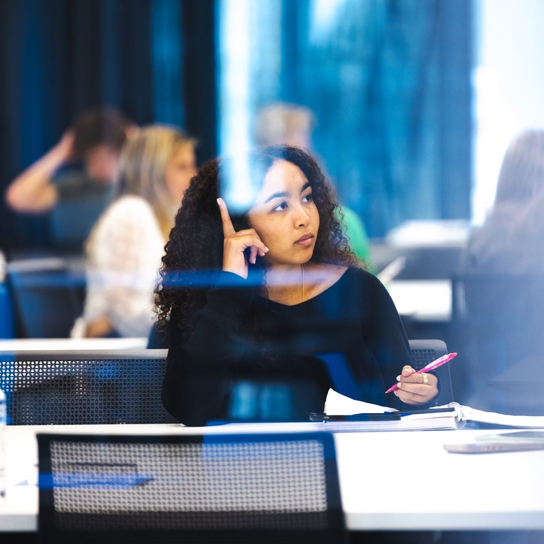 A student listens to a class lecture while taking notes