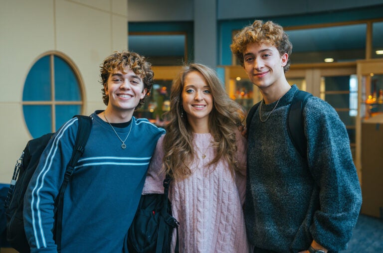 Triplets John, Madison and Zachary Apostolon stand together in Marshall University's Drinko Library