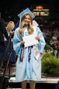 Anna-Kay Dean smiles with her diploma at her high school graduation