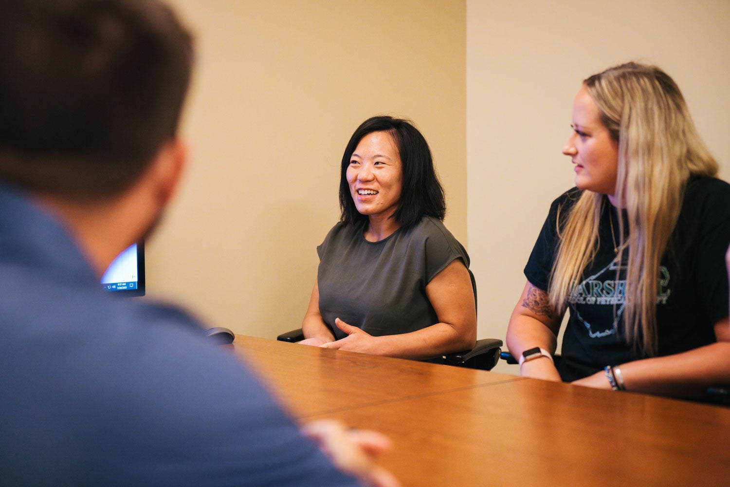 two students talking to a professor at a desk