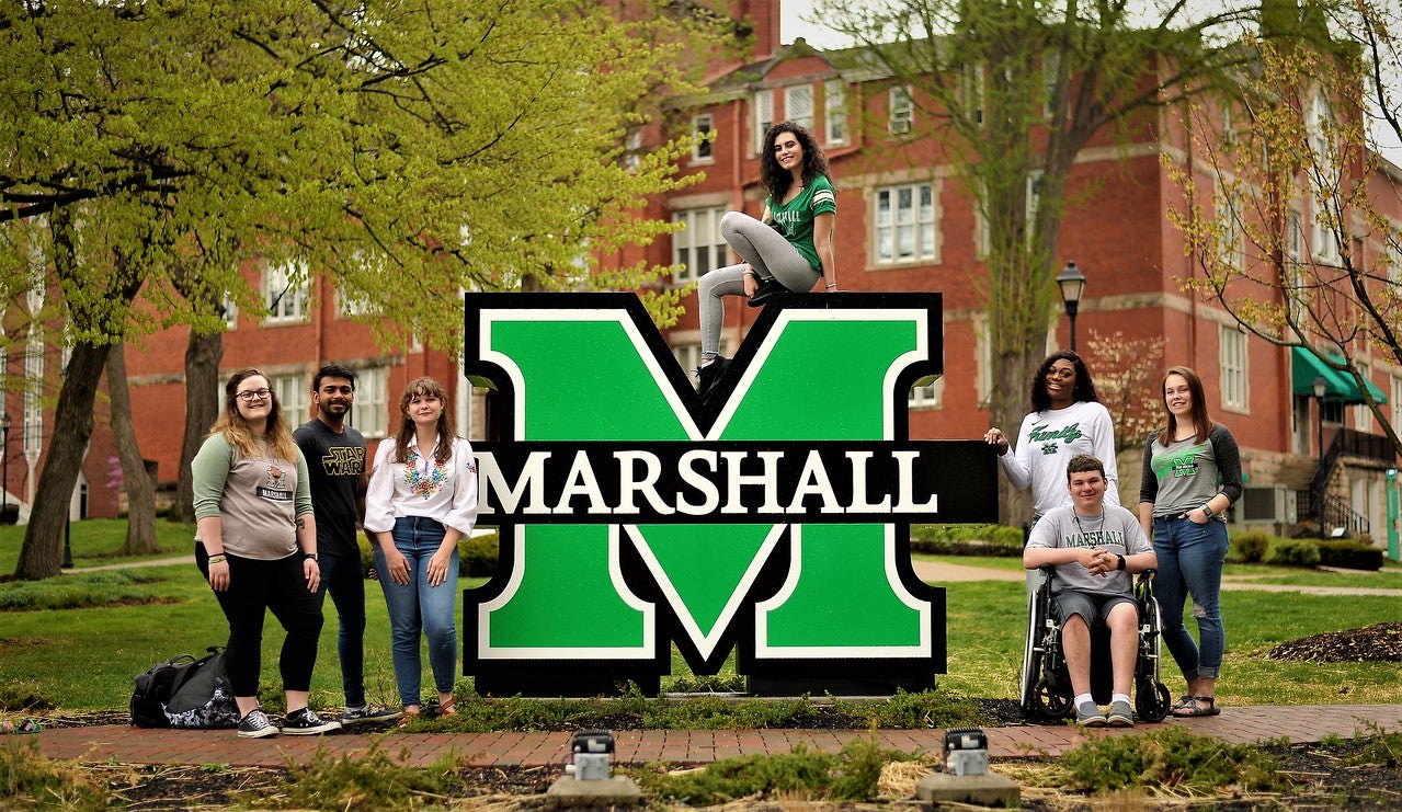 A group of students at a Marshall sign on Marshall's Huntington campus